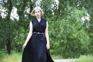 zeventien jaar oud blond meisje in een zwart jurk Aan een zomer achtergrond. afstuderen. foto