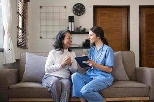 Aziatisch verpleegster tonen Gezondheid controle verslag doen van naar oma en geven het advies. medisch bijgestaan leven bezoek senior geduldig Bij huis. huis verpleging en gezondheidszorg verzorger concept foto