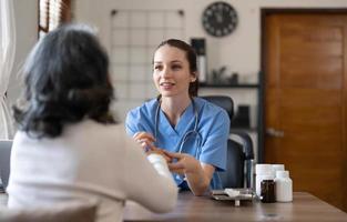 Aziatisch vrouw dokter onderzoeken en nemen Notitie Aan checklist papier met vrouw patiënten in medisch kamer. foto