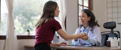 midden- oud vrouw kinderarts luisteren naar jong vrouw klachten met Gezondheid problemen en schrijven naar beneden Aan de medisch geschiedenis papier gedurende de behandeling. Gezondheid concept foto