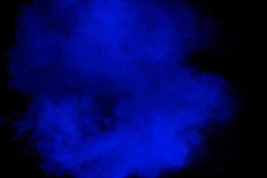 blauw poeder explosie wolk Aan zwart background.gelanceerd blauw stof deeltje plons. foto