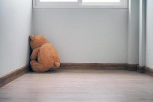 kind concept van leed. teddy beer zittend leunend tegen de muur van de huis alleen, kijken verdrietig en teleurgesteld. foto
