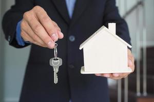 huiseigenaren zijn leveren huis sleutels naar huurders of kopers. huis verkoop concept foto