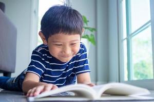 de weinig jongen is lezing een boek in de huis Oppervlakte. aan het leren Bij huis foto