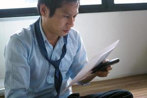 een Aziatisch bedrijf Mens heeft een benadrukt gezicht met documenten gehouden in zijn hand. foto