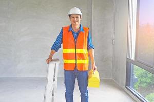 een civiel ingenieur houdt een gereedschapskist en een medium ladder naar bereiden voor werk of naar reparatie of inspecteren een huis. foto