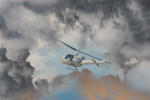 een redden helikopter races tegen een tegemoetkomend storm erge, ernstige weer, modern aanval helikopter met met wapens foto