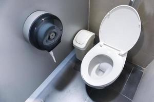 toilet kom in een modern badkamer met bakken en toilet papier, spoelen toilet schoon badkamer foto