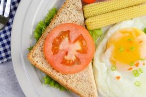 een gebakken ei met toast, worteltjes, babymais en lente-uitjes foto