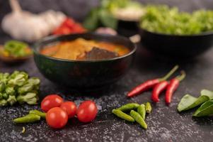 kipcurry in een zwarte kop, compleet met tomaten en chili foto