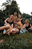 Javaans mensen met traditioneel dans kostuums houdende naar beneden Aan de gras samen gedurende de foto schieten