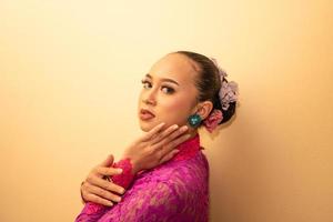 Aziatisch vrouw in een roze jurk proberen naar slijtage een groen oorbel in haar oren foto