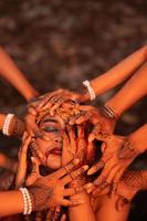 verdrietig Mens gezichten gedekt omhoog door een veel van handen met henna- tatoeages terwijl vervelend een goud kroon foto