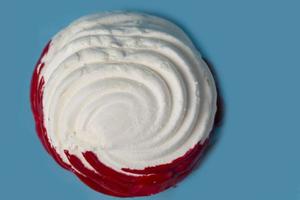 wit heemst gedekt met rood suikerglazuur Aan een blauw achtergrond detailopname. foto