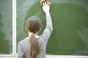 een midden- school- of junior hoog school- leerling doekjes de schoolbord. foto