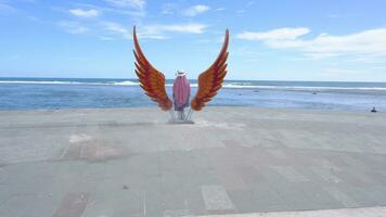vrouw staand in de midden- van een vleugel standbeeld Aan de strand foto