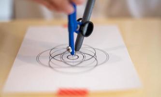 vrouw hand- gebruik makend van een meten cirkel voorbereidingen treffen naar trek en schetsen de mandala concept Aan de leeg wit papier. foto