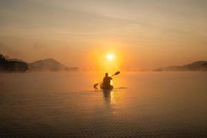 Dames Aan kajak rijen in de reservoir gedurende de zonsopkomst, harak Woud park huai naam Mens reservoir loei Thailand 21 jan 2023 foto