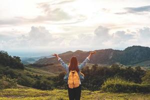 gelukkige jonge vrouw reiziger ontspannen en kijken naar de prachtige zonsondergang op de top van de berg foto