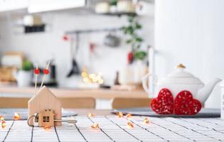 sleutel naar huis van knus huis met Valentijn decor Aan tafel van keuken. geschenk voor valentijnsdag dag, familie liefde nest. gebouw, ontwerp, projecteren, in beweging naar nieuw huis, hypotheek, huur en aankoop echt landgoed foto