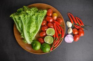 plakjes limoen, sjalotjes, knoflook, tomaten, sla en paprika op een houten bord