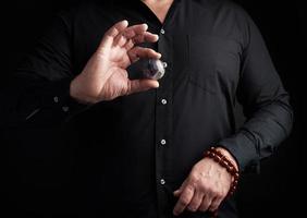 Mens in een zwart overhemd houdt een steen bal voor religieus rituelen, meditaties foto
