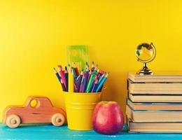 achtergrond terug naar school- met kinderen schrijfbehoeften potloden, boeken, appel, glas wereldbol foto