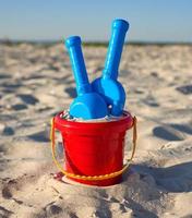 rood plastic emmer en blauw hark, Schep Aan de zand foto