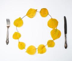 vork, mes en ronde krans van geel droog abrikoos bladeren foto