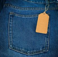 gebonden Aan een touw is een leeg rechthoekig bruin papier label Aan blauw jeans foto