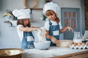 gebruikt zeef. familie kinderen in wit chef uniform voorbereidingen treffen voedsel Aan de keuken foto