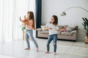 dansen samen. kinderen hebben pret in de huiselijk kamer Bij dag foto