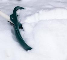 plastic groen Schep plakken uit van een stapel van sneeuw foto