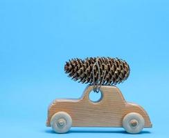 houten speelgoed- auto draagt Aan top een pijnboom ijshoorntje Aan een blauw achtergrond foto