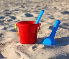 rood plastic emmer en blauw hark, Schep Aan de zand foto