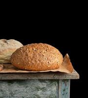 gebakken ronde rogge brood leugens Aan een bruin papier foto