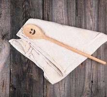 houten lepel met een grappig glimlach leugens Aan een wijnoogst textiel handdoek foto