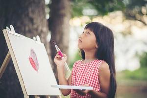 klein meisje kunstenaar schilderen van een foto in het park