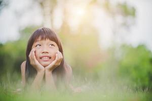 klein meisje comfortabel op gras liggen en glimlachen foto