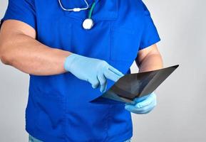 dokter in blauw uniform en steriel latex handschoenen houdt en onderzoekt röntgenstraal foto