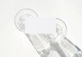 blanco bedrijf kaart mockup Aan glas met schaduw van natuurlijk bladeren schaduw bedekking Aan wit achtergrond, voor Product of presentatie foto