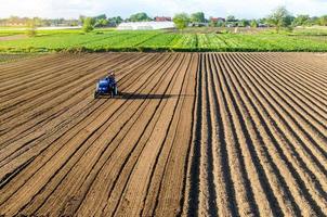 trekker Aan bouwland veld. boerderij werk. frezen bodem, verzachtend de bodem voordat aanplant nieuw gewassen. ploegen. losmaken oppervlak, land- teelt. mechanisatie in landbouw. snijdend rijen voor planten. foto