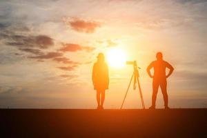silhouet van een fotograaf met model en camera bij zonsondergang foto