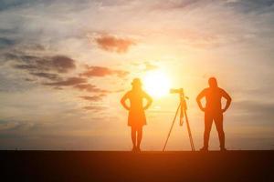 silhouet van een fotograaf met model en camera bij zonsondergang foto