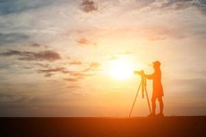 silhouet van een fotograaf fotograferen bij zonsondergang foto