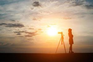 silhouet van een fotograaf fotograferen bij zonsondergang foto