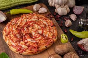 pizza op een houten bord met paprika, knoflook, chili en shiitake champignons