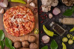 pizza op een houten bord met paprika, knoflook, chili en shiitake champignons