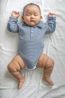 een babyjongen in een gestreept shirt die in bed slaapt foto