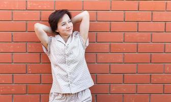 vrolijk vrouw in huis slijtage pyjama- buitenshuis steen muur achtergrond emoties kopiëren ruimte en leeg plaats voor tekst - nachtkleding en huiskleding concept foto